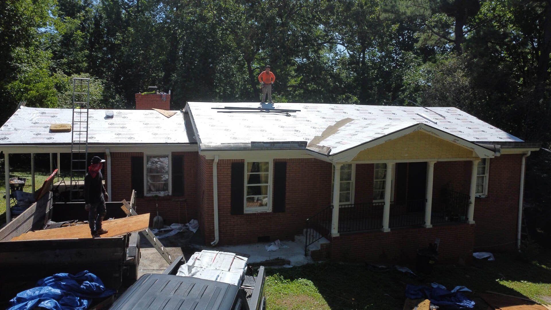 A man is working on the roof of a brick house