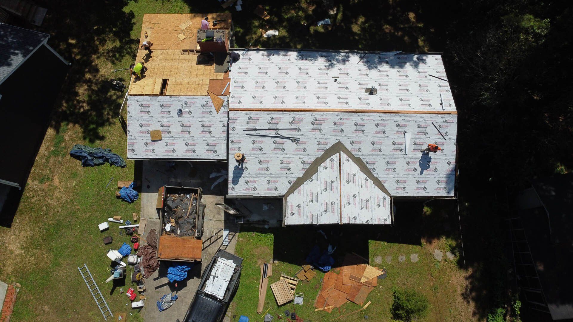 An aerial view of a house under construction with workers on the roof.