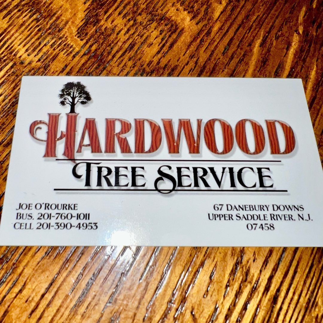 Hardwood Tree Service business card on wood surface with red and black logo and contact details