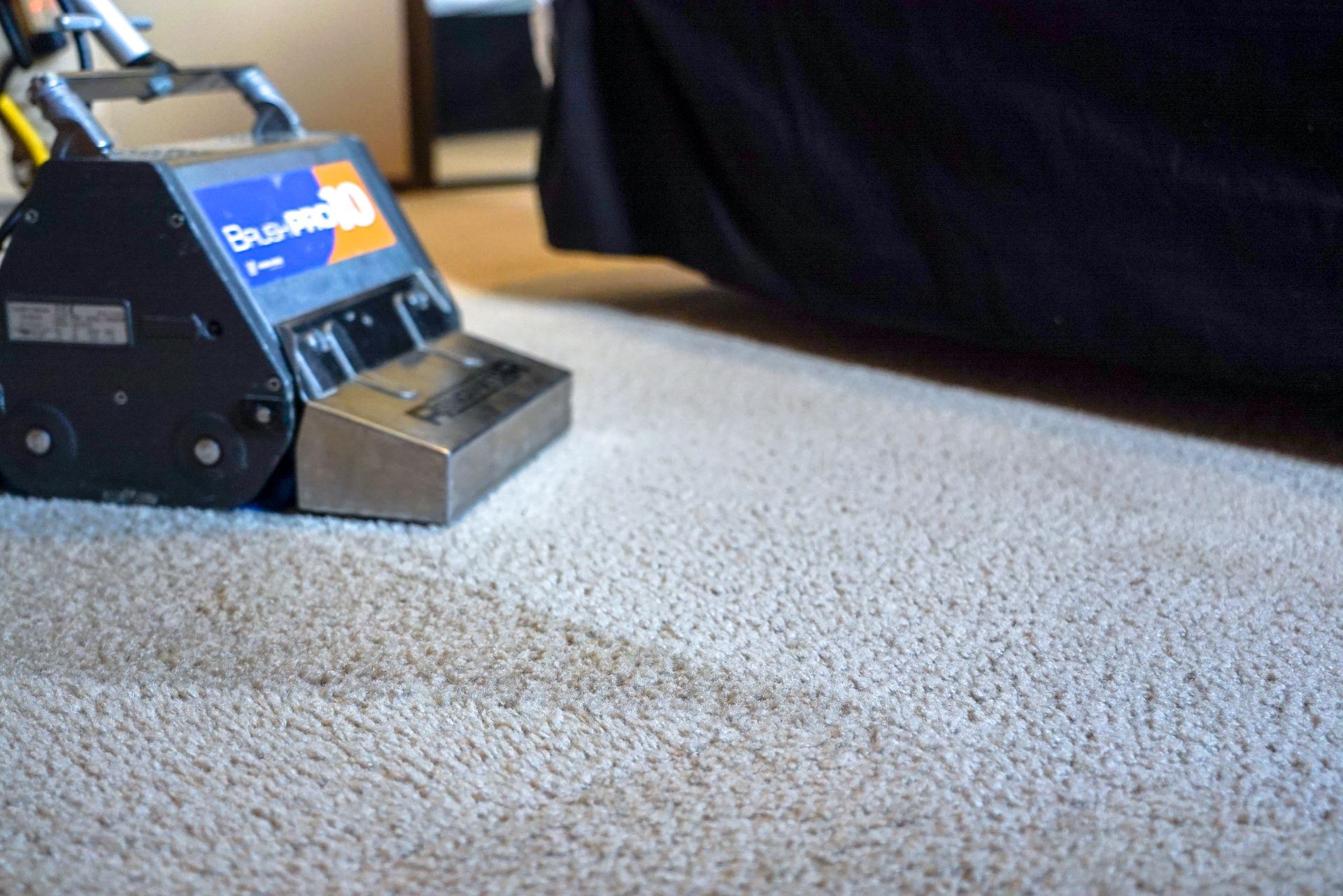 A vacuum cleaner is cleaning a carpet in a living room.