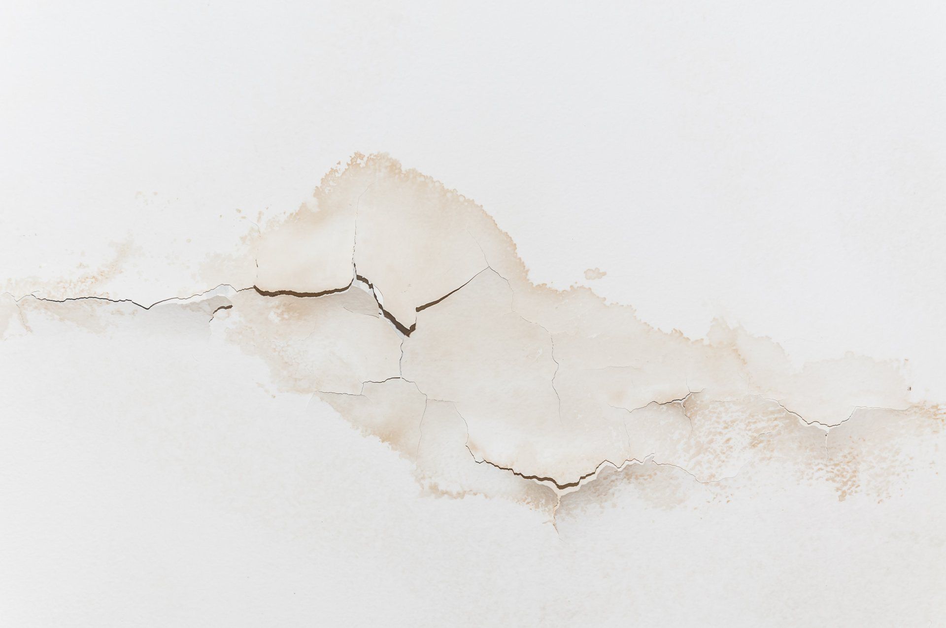A close up of a white wall with water stains on it.