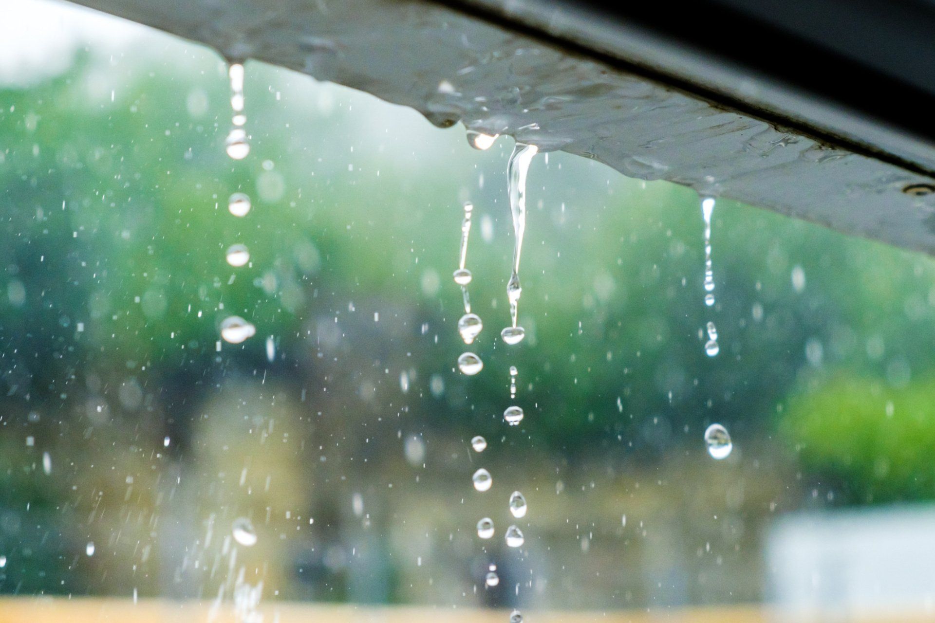 Rain is falling from the roof of a building.