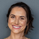 A woman is smiling for the camera with a gray background.