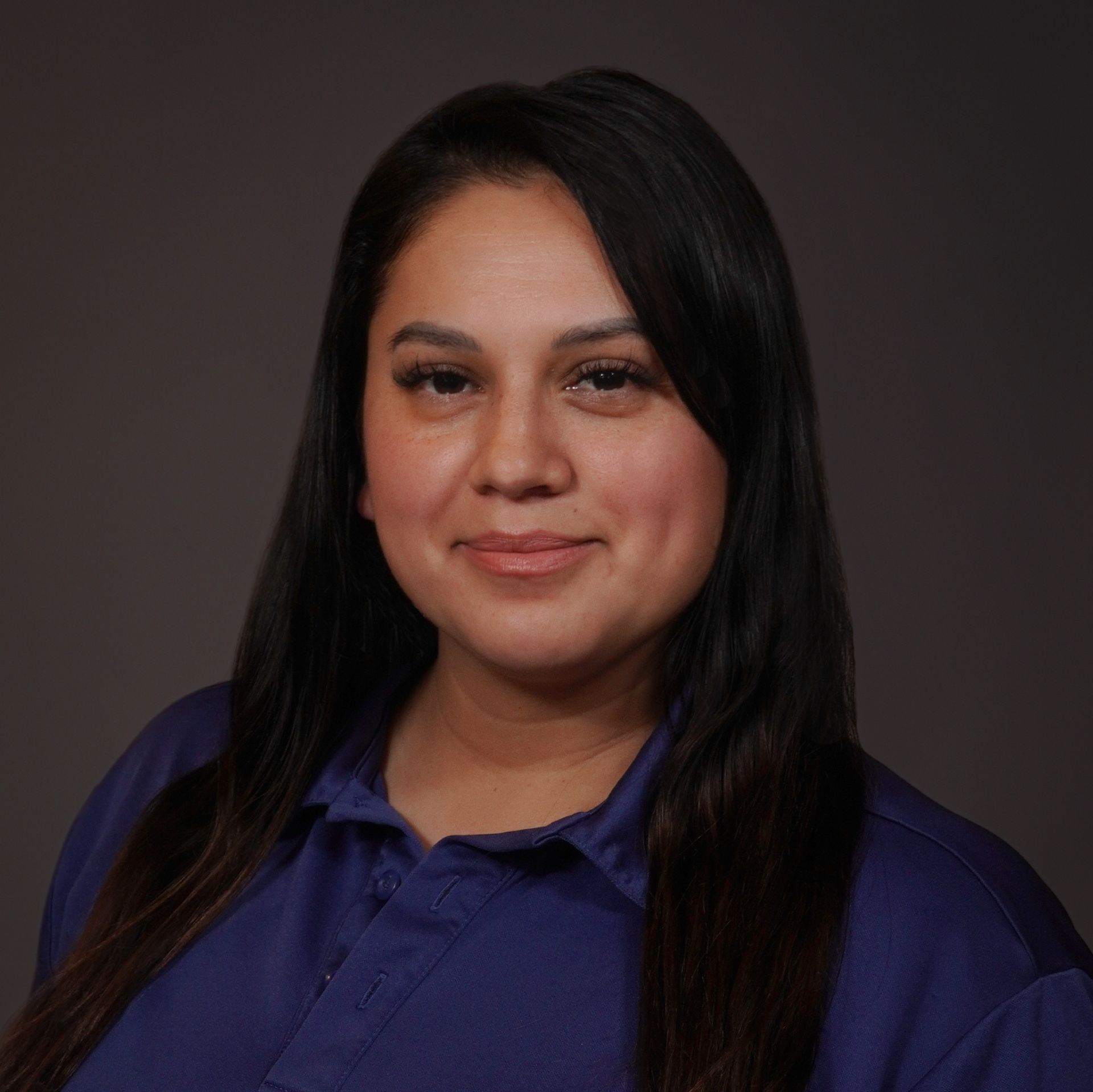 A woman in a purple shirt is smiling for the camera.