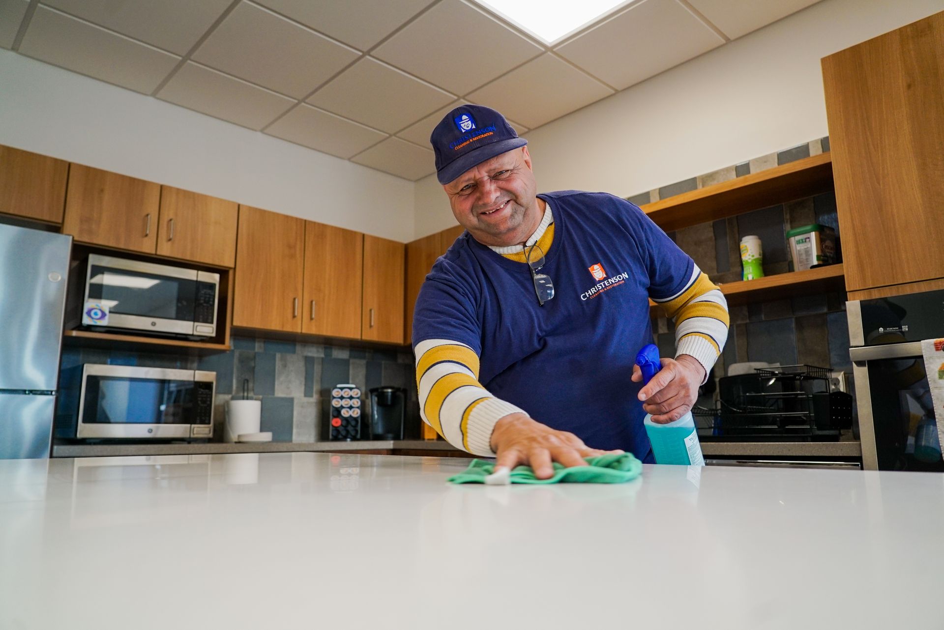 A man is cleaning a counter in a kitchen.