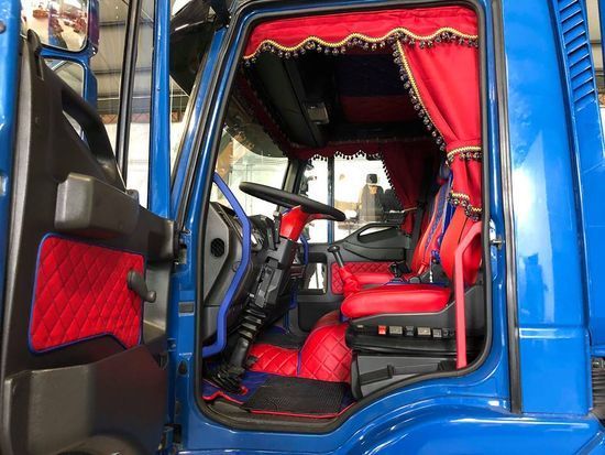 L'interno di un camion blu con sedili e tendine rossi.