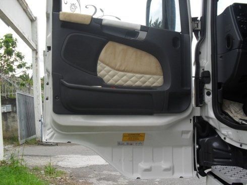 La portiera di un camion bianco è aperta e ha un cuscino di seduta trapuntato.