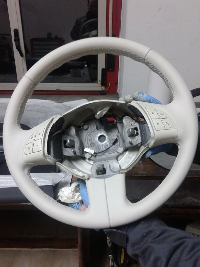 Una persona tiene in mano un volante bianco con dei pulsanti