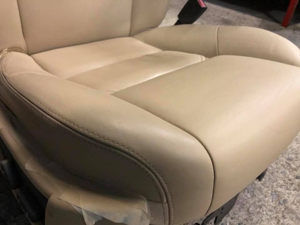 Primo piano di un sedile per auto in pelle marrone chiaro su un tappeto.