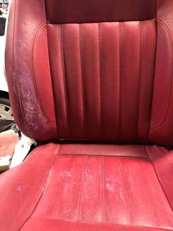 Un sedile di pelle rossa per auto è appoggiato su un tavolo.