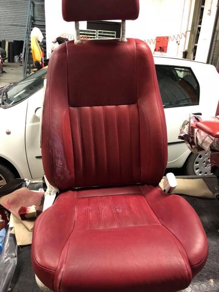 Un sedile di pelle rossa è posizionato davanti a un'auto bianca.