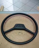 Un volante nero è appoggiato su un tavolo di legno.