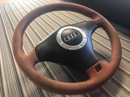 Un volante Audi in pelle marrone è appoggiato su un tappeto a righe.