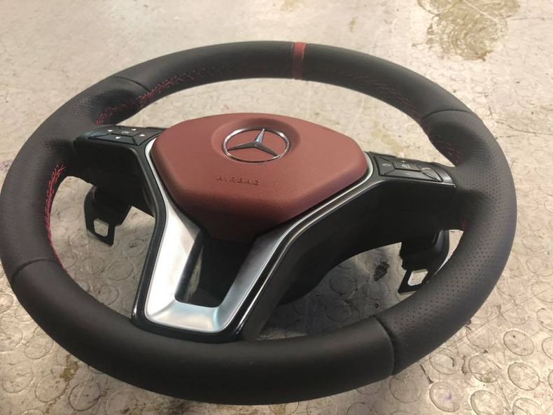 Un volante nero con il logo Mercedes rosso sopra