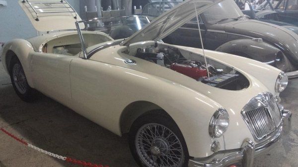 Un'auto bianca con il cofano alzato è parcheggiata accanto a un'altra auto
