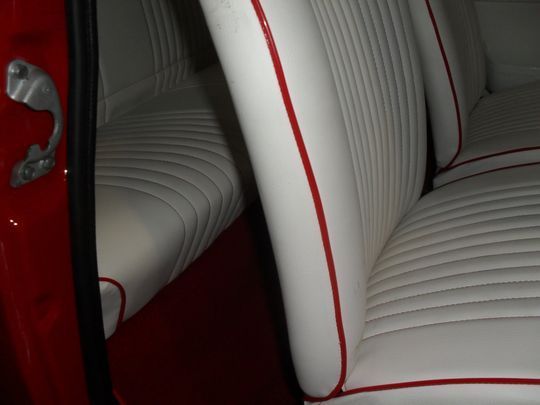 Un'auto rossa con sedili bianchi e finiture rosse