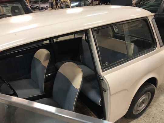 Un'auto bianca con sedili blu e bianchi è parcheggiata in un garage