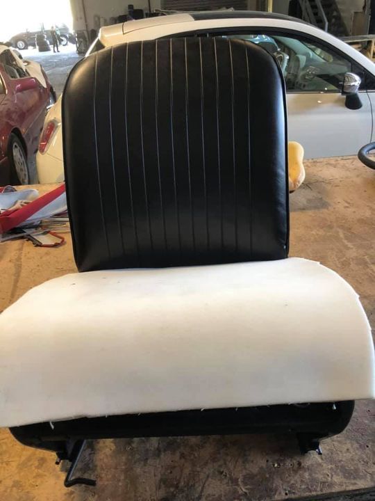 Una sedia bianca e nera è appoggiata su un tavolo di legno accanto a un'auto.