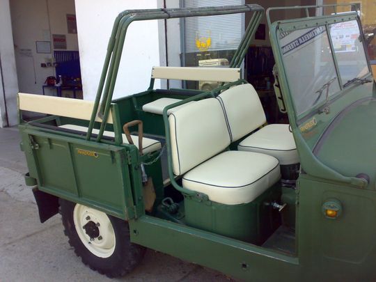 Un veicolo verde con sedili bianchi è parcheggiato davanti a un edificio