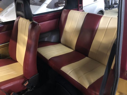 Il sedile posteriore di un'auto con sedili rossi e beige