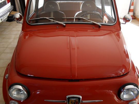 Un'auto Abarth rossa è parcheggiata in un garage