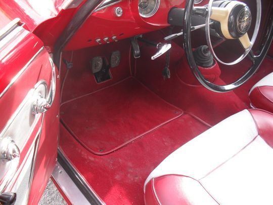 Un'auto rossa con sedili bianchi e un volante