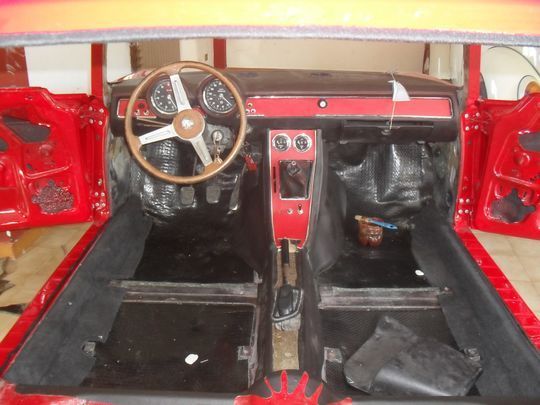 L'interno di un'auto rossa con volante in legno