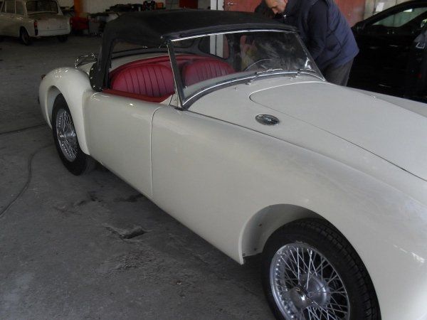 Un'auto bianca con i sedili rossi è parcheggiata in un garage