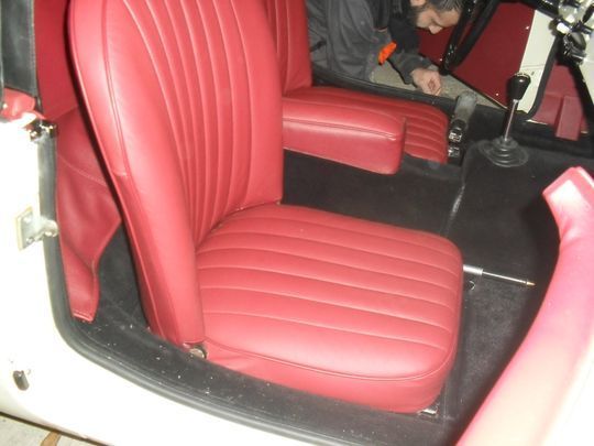 Un'auto bianca con sedili rossi e un volante
