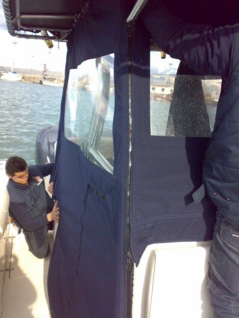 Un uomo con una giacca blu è inginocchiato su una barca