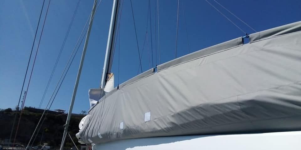 Una barca a vela con una vela grigia e un cielo azzurro sullo sfondo.