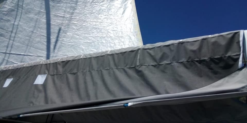 Un primo piano della vela di una barca con un cielo azzurro sullo sfondo.