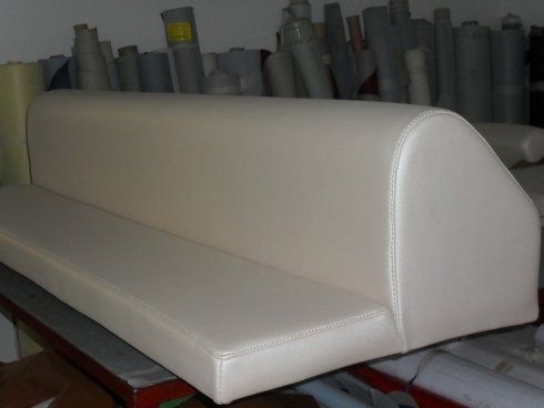 Un divano bianco è appoggiato davanti a rotoli di tessuto