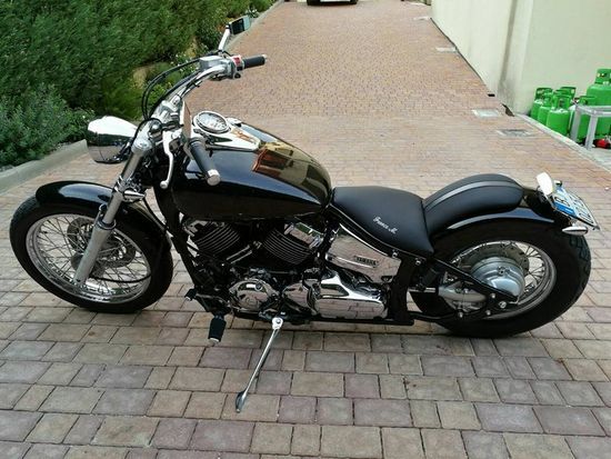 Una motocicletta nera è parcheggiata su un vialetto di mattoni