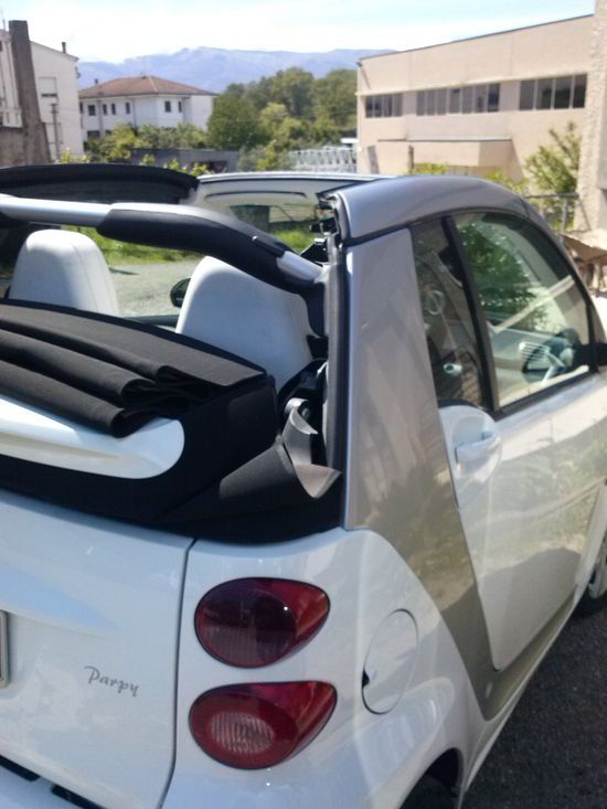 Una smart con capote è parcheggiata davanti a un edificio