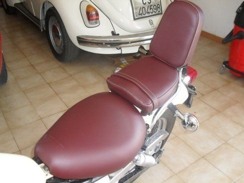 Una motocicletta con un sedile rosso e un'auto bianca sullo sfondo