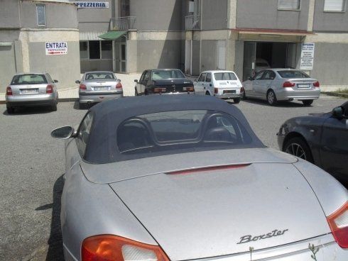 Una porsche boxster argentata è parcheggiata in un parcheggio