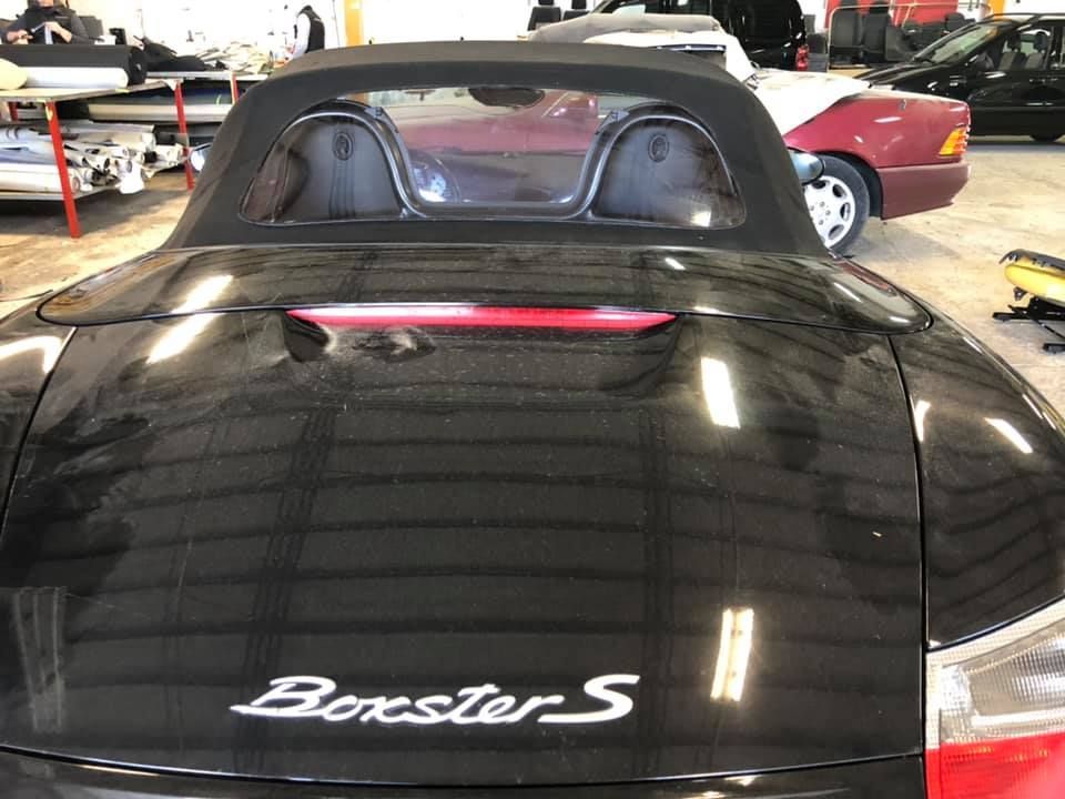Una porsche boxster s nera è parcheggiata in un garage.