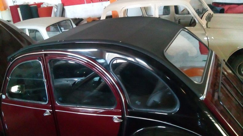 Un'auto rossa con il tetto nero è parcheggiata in un garage