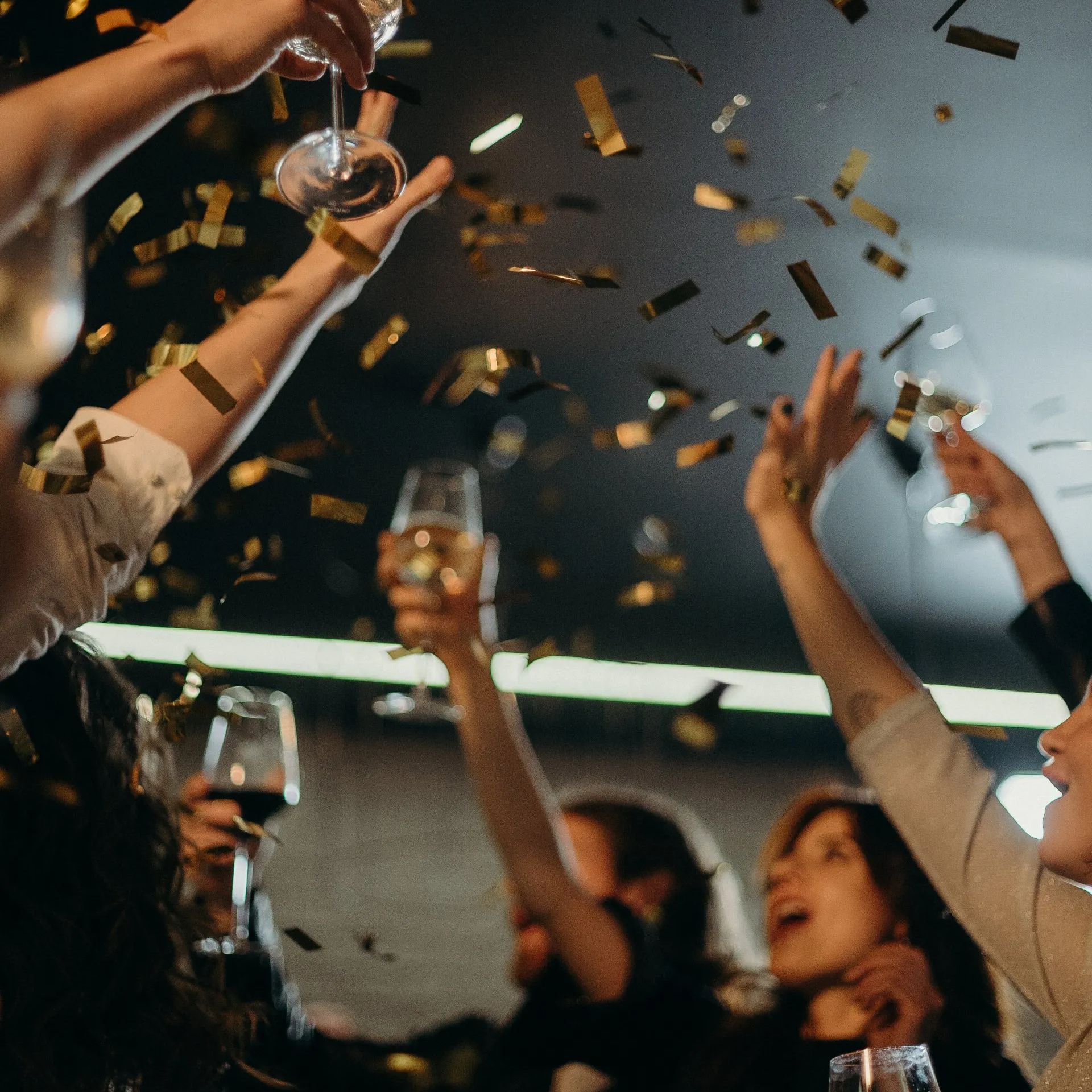 Een groep mensen houdt champagneglazen vast en gooit confetti in de lucht.