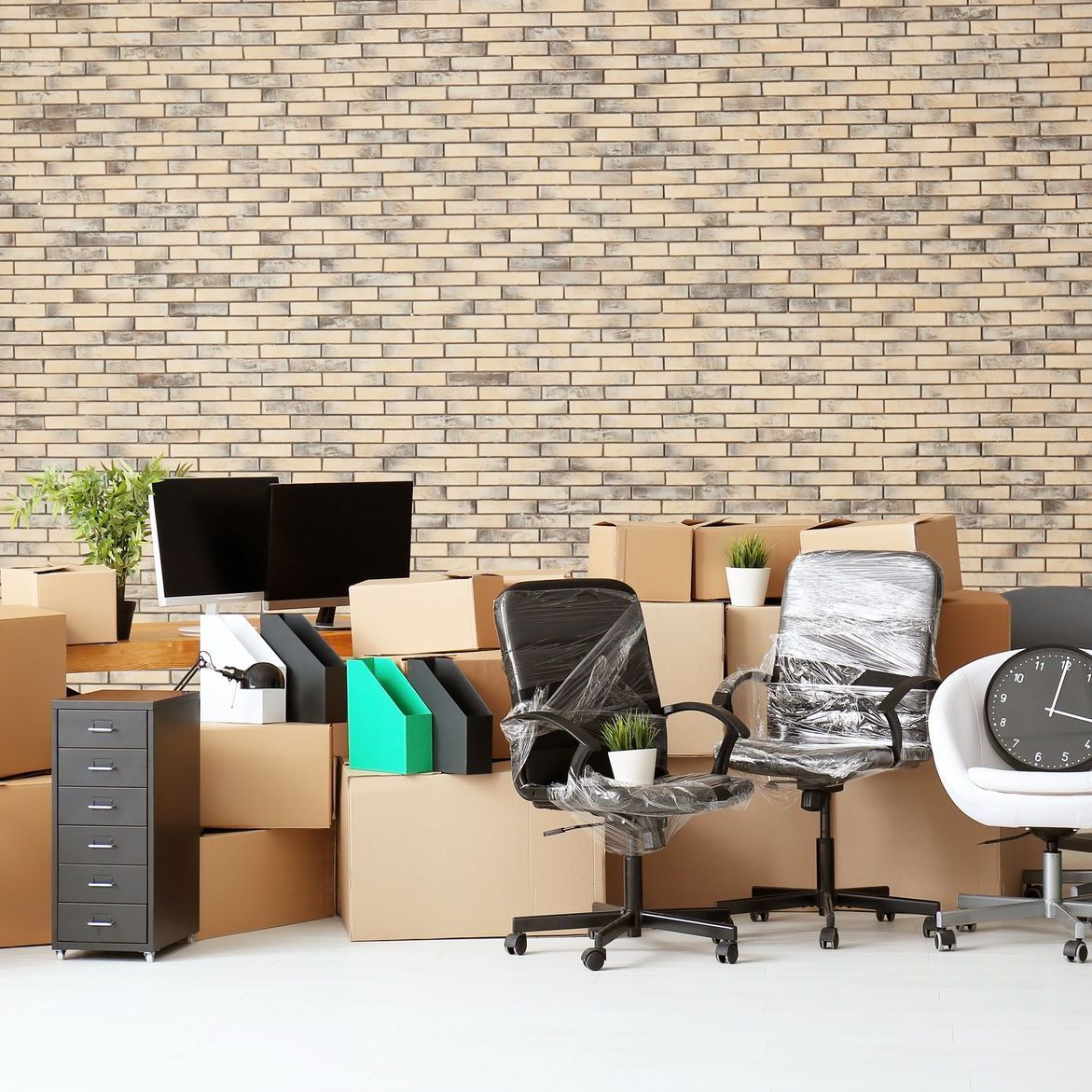 Een rij bureaustoelen en dozen in een kantoor met een bakstenen muur.