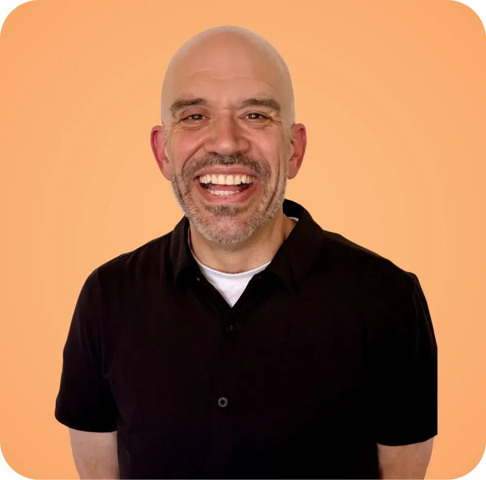A bald man with a beard is smiling and wearing a black shirt.