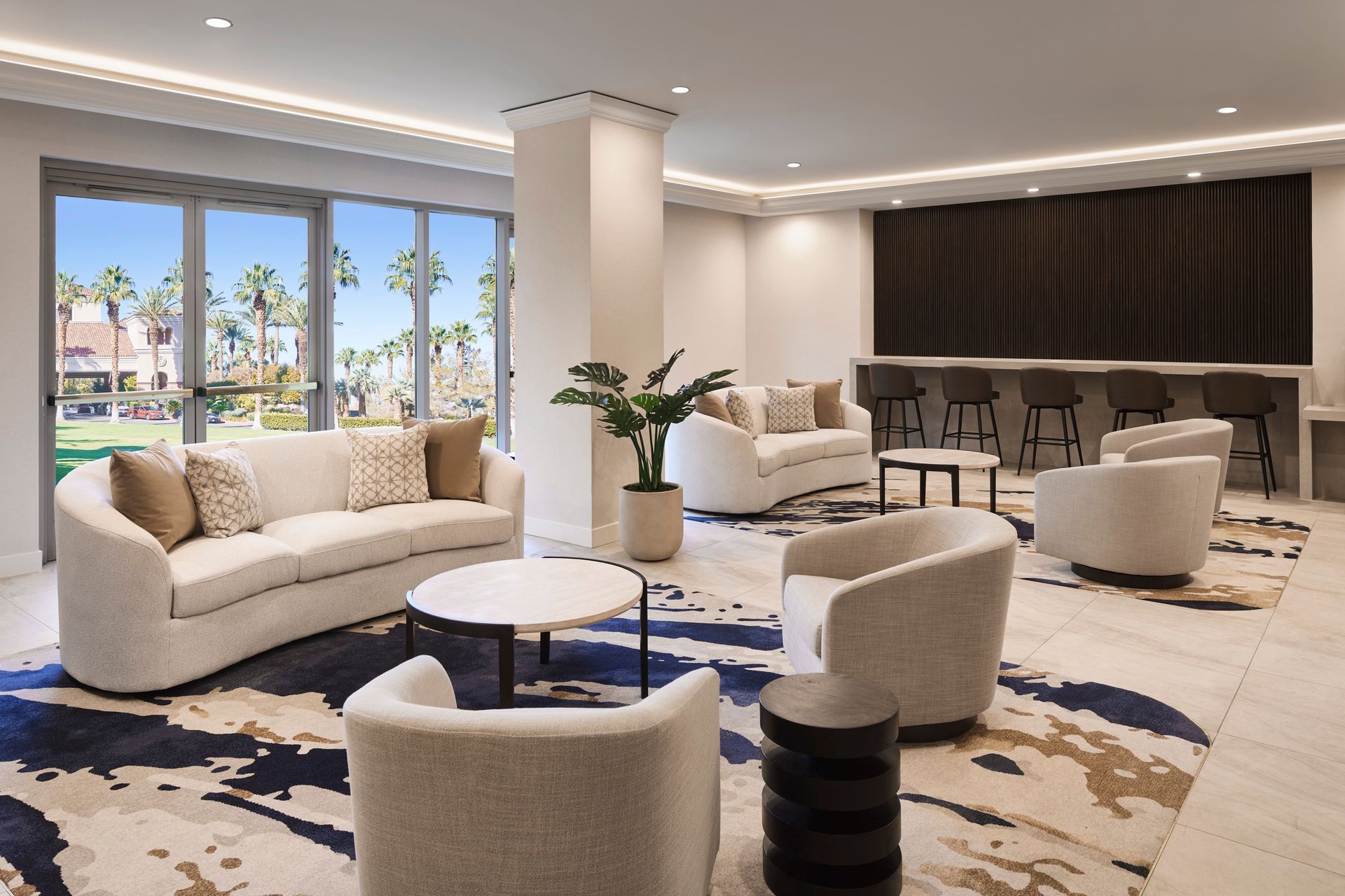 A living room with a couch , chairs , tables and a large window.