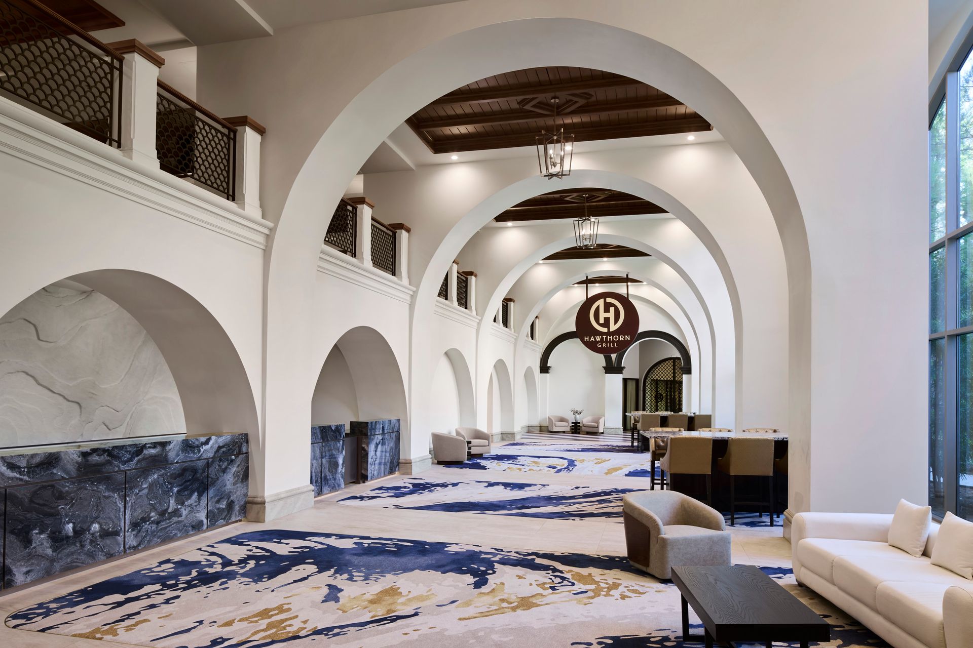 A long hallway with arches and a couch and chairs