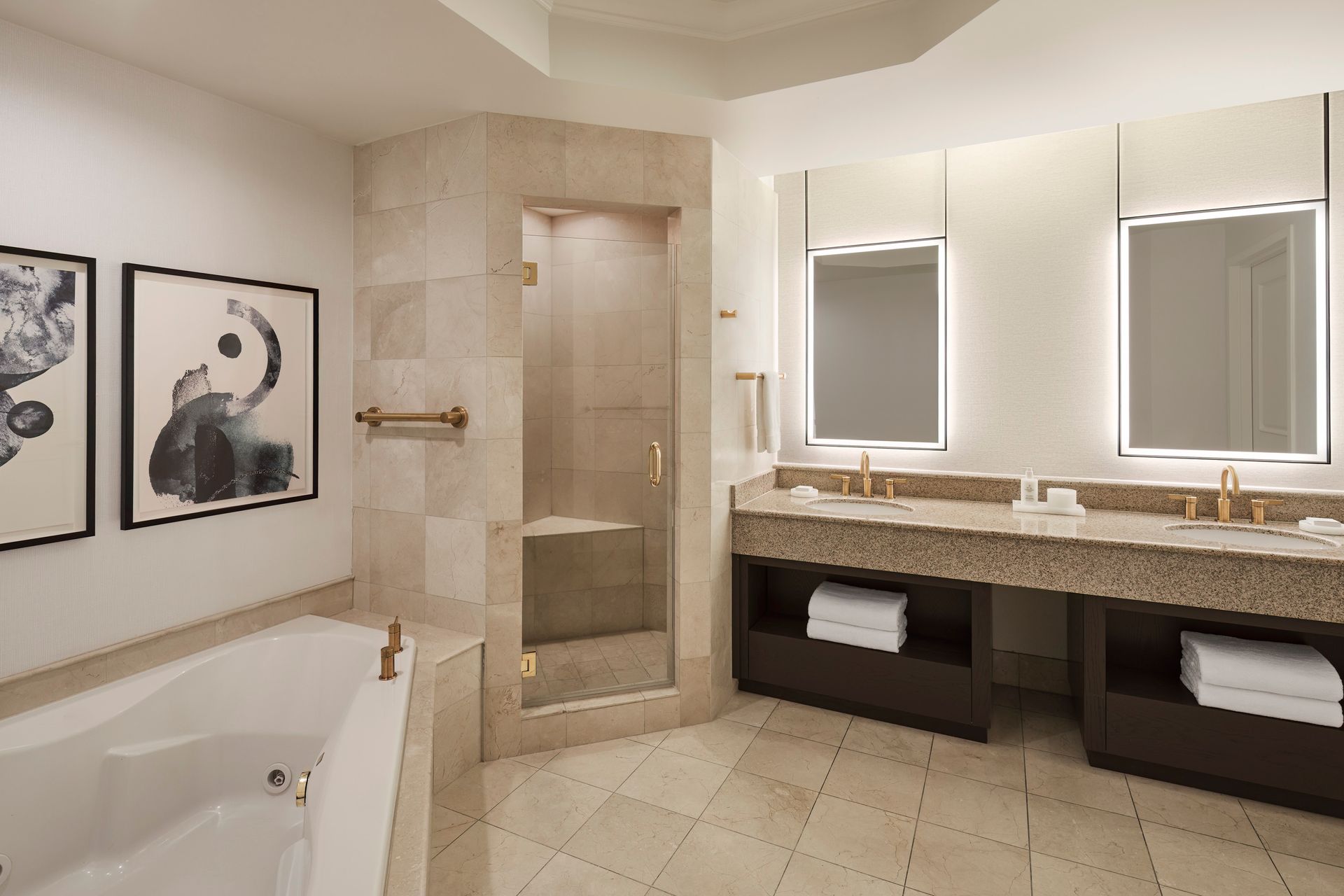 Spacious, modern bathroom with a jacuzzi tub, walk-in shower, and double vanity with mirrors. Beige tile and neutral tones.