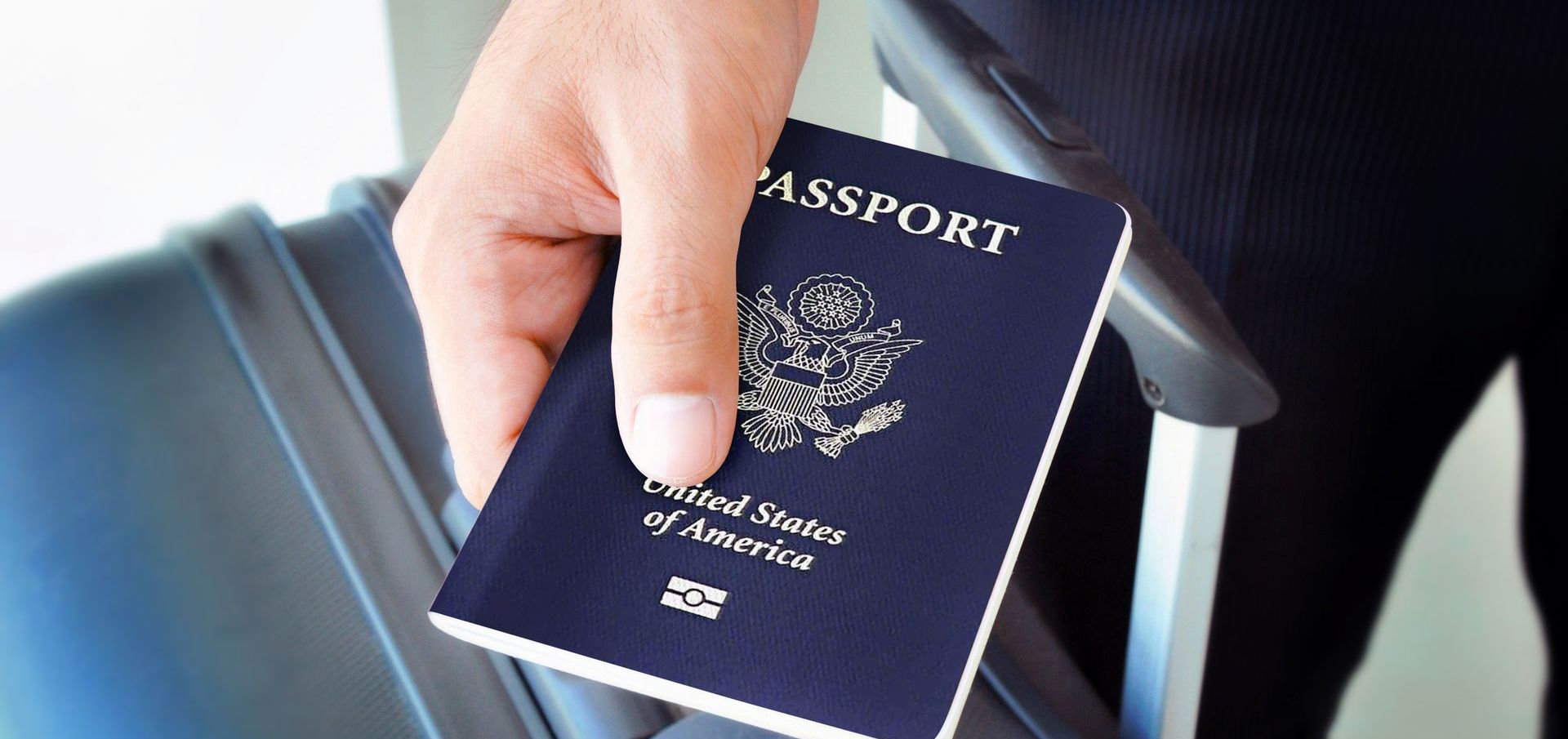 Person holding a United States passport, likely at an airport. The passport is dark blue.