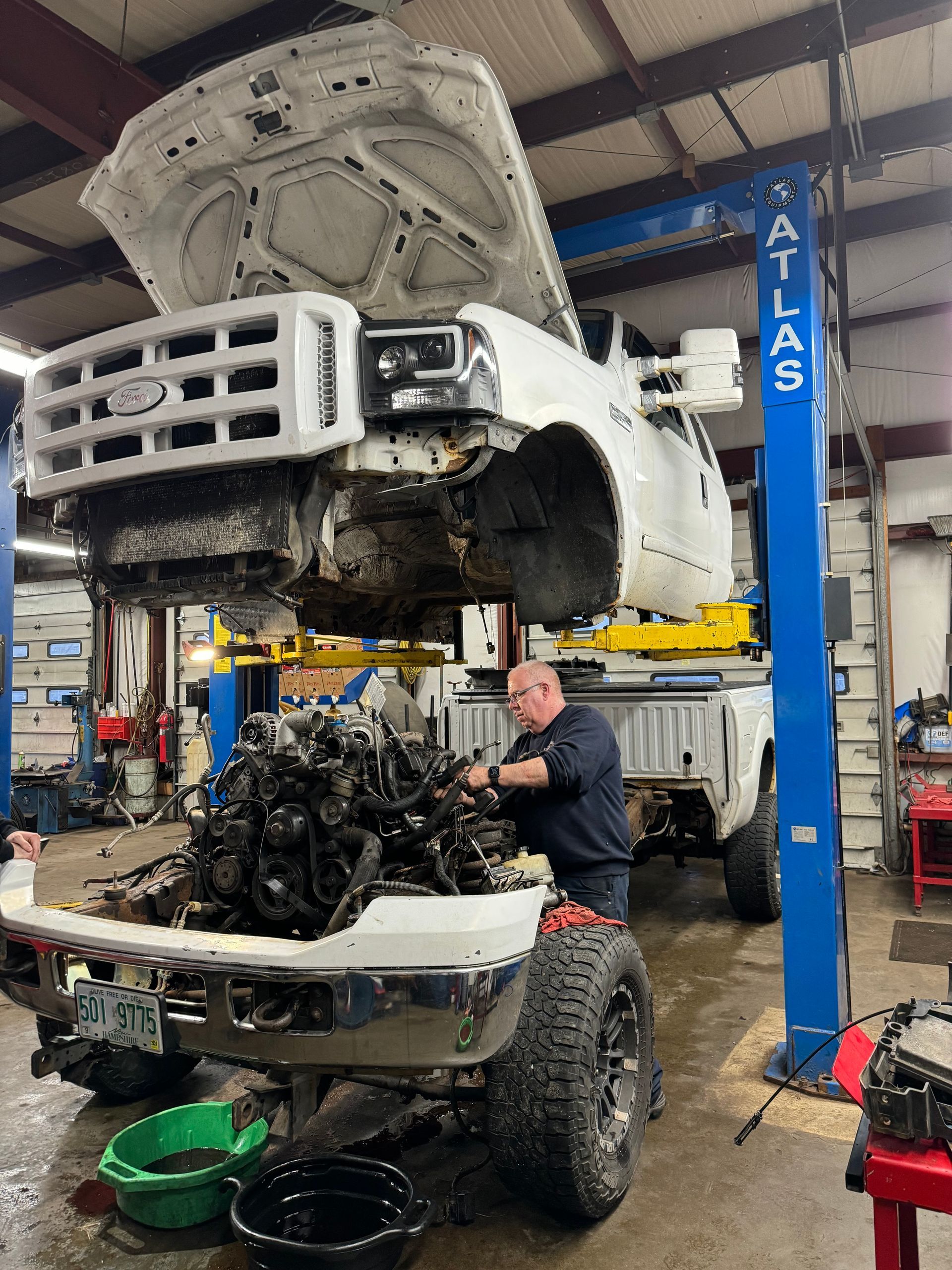 A mechanic works on a white Ford truck  | Keegan Auto