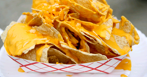 A tray of nachos covered in cheese on a table.