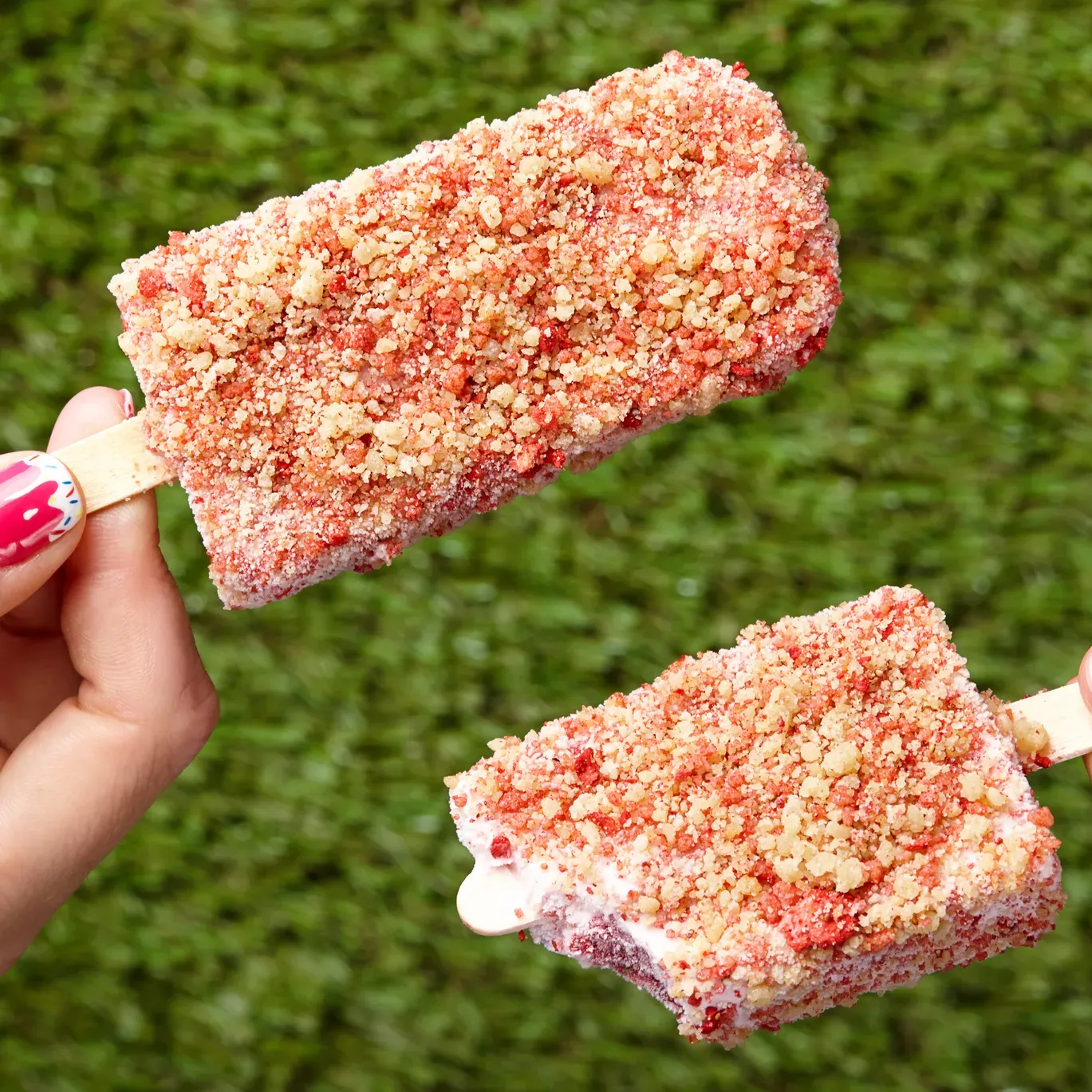 A person is holding two ice cream bars with nuts on them | Ice Cream Cart Rentals
