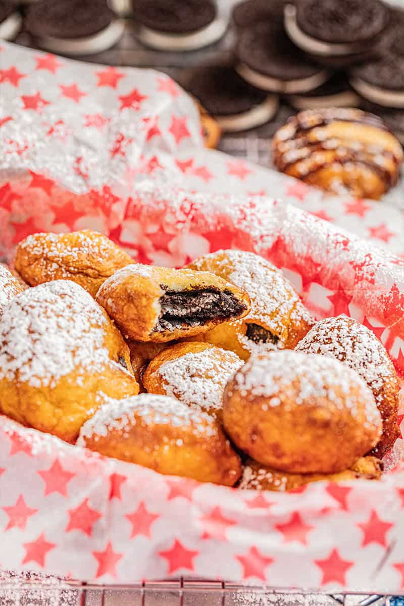 A basket filled with oreo doughnuts covered in powdered sugar.